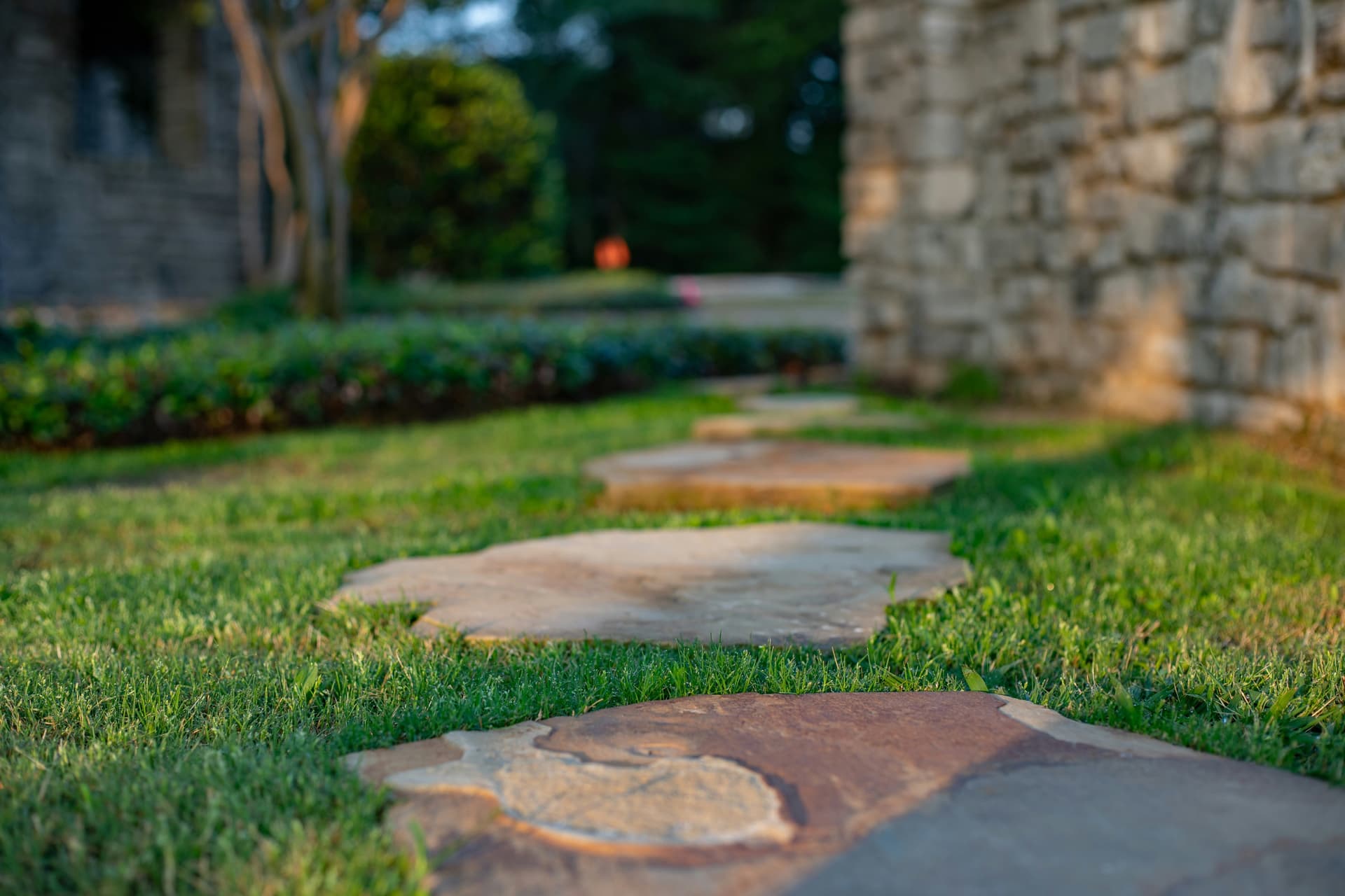 Natural stone stepping stones set into a manicured lawn at golden hour